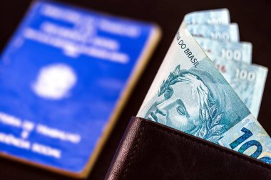 Brezilya 'dan siyah deri cüzdanlı 100 reais banknot, siyah arka planda izole edilmiş, Brezilya' dan eski bulanık iş kartı.