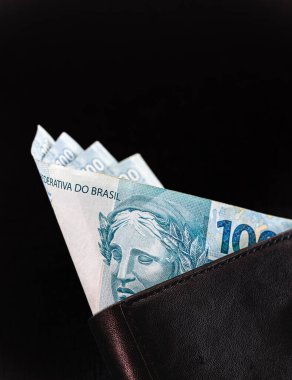 Brezilya 'dan 100 reais siyah arka planda izole edilmiş siyah deri cüzdanlı banknotlar