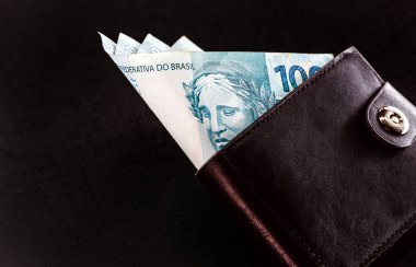 Brezilya 'dan 100 reais siyah arka planda izole edilmiş siyah deri cüzdanlı banknotlar