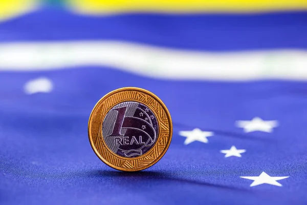 one brazilian real coin with brazil flag in the background. Brazil economy concept