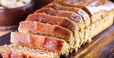 Ev yapımı vejetaryen ekmeği, sade ahşap masada dilimlenmiş. Muz aromalı. Glütensiz yiyecek veya hayvansal ürünler.