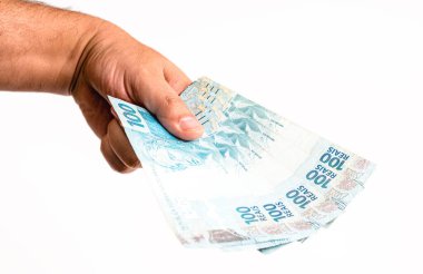Brezilya 'dan 100 reais banknot, izole edilmiş beyaz arka planda erkek eliyle tutulmuş. Brezilya 'dan 100 reais' in banknotları, ödeme günü..