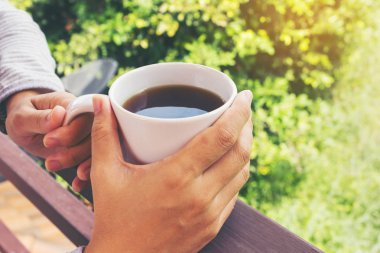 Ellerini almak büyük fincan sıcak siyah kahve güneşli gün dinlenmek