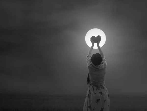 kadın yavaşça kırmızı kalp güneşe doğru tutun. 