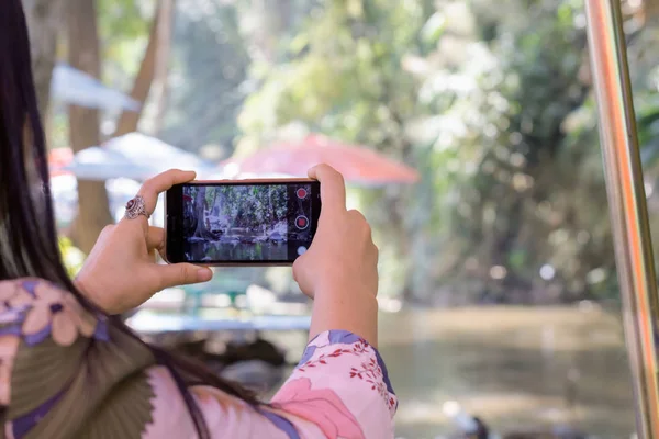 Hand shooting video clip of waterfall, lifestyle with smartphone