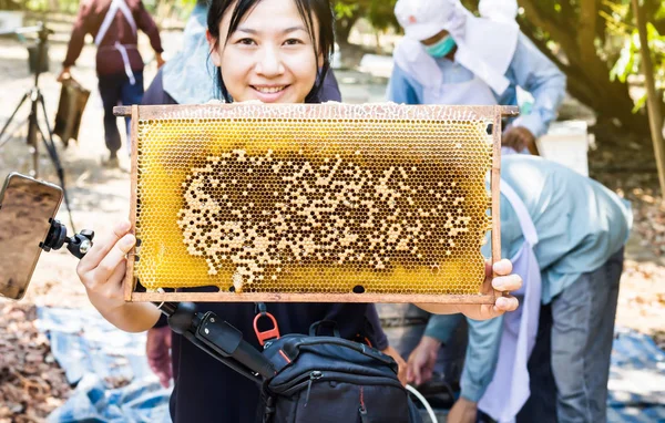 Großer Bienenstock präsentiert von lächelnden asiatischen Frauen mit Bäuerinnen worki — Stockfoto