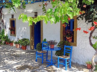 House in Kos with in the typical for Greece blue-painted furniture in front of it clipart