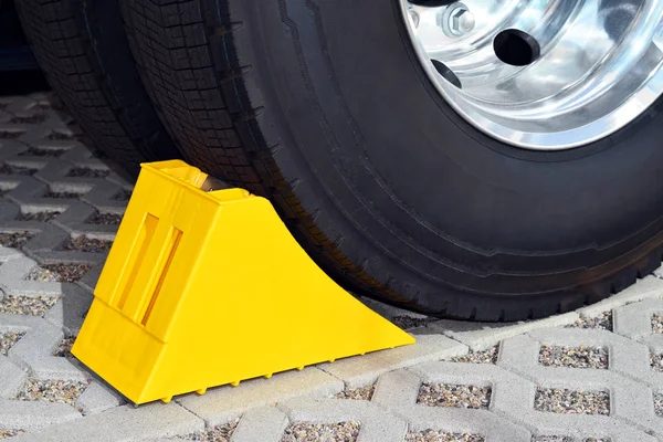 Yellow chock at the wheel of a parked truck — Stock Photo, Image