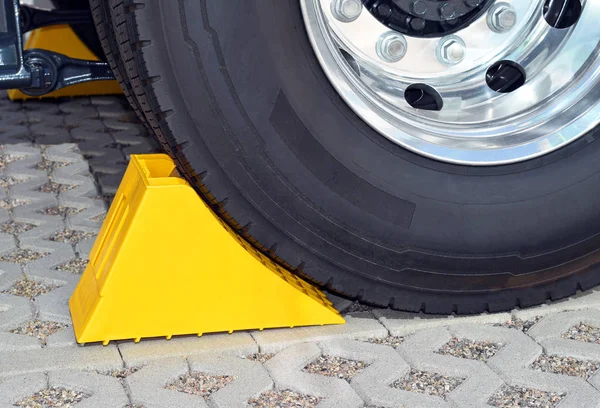 Yellow chock at the wheel of a parked truck — Stock Photo, Image