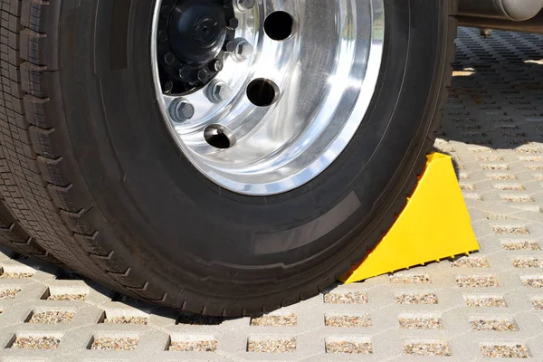 Yellow chock at the wheel of a parked truck — Stock Photo, Image