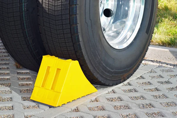 Yellow chock at the wheel of a parked truck — Stock Photo, Image