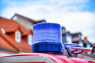 Detailed view of a blue rotating beacon on the roof of a red fire truck clipart
