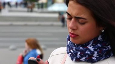 Beyaz yağmurluk içinde güzel bir kızın dudaklarına ruj ile boyar. Dudaklarını kırmızı ve seksi bir yeni glamour ruj sokakta tarafından üstünde belgili tanımlık ayna yapmak ararken çekici genç bayan.