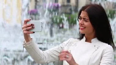Smartphone kullanarak gülen kız portresi. Cep telefonu çeşme arka plan üzerinde olan genç ve güzel kadın. Şehir Parkı, atış Steadicam Smartphone kullanan oldukça mutlu kadın.