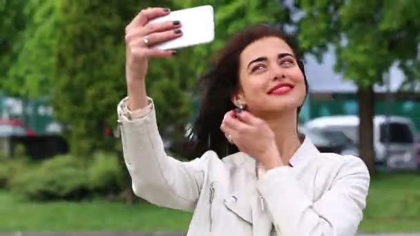 Retrato de menina rindo usando smartphone. Uma jovem bonita com o telemóvel no fundo da fonte. Mulher muito feliz usando smartphone no parque da cidade, Steadicam tiro . — Vídeo de Stock