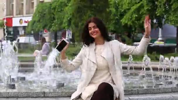 Jolie jeune femme avec son téléphone portable sur fond de fontaine . — Video