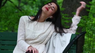 Kadın bir parkta kulaklık ile bir akıllı telefondan müzik dinlerken.