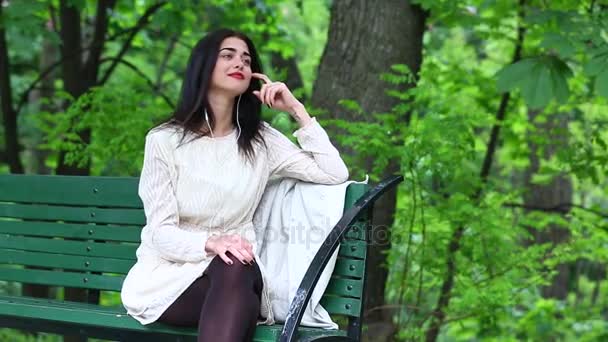 Женщина слушает музыку со смартфона с наушниками в парке . — стоковое видео