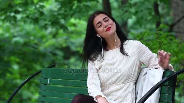 Donna che ascolta la musica da uno smartphone con cuffie in un parco, bella donna che utilizza smartphone con cuffie — Video Stock