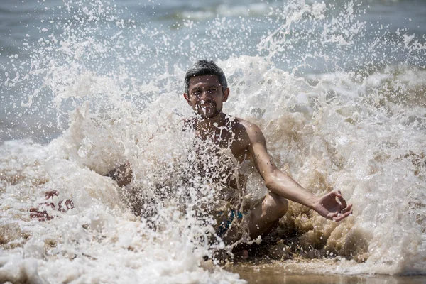 Kaslı fit vücut gösterilen Goa, Hindistan, tişörtsüz giyiyorsun boxer şort, bir plajda durup yakışıklı genç adam. Seksi adam okyanus tarafından geliyor. Gerçek köpük ve su damlaları ile mükemmel reklam için. — Stok fotoğraf