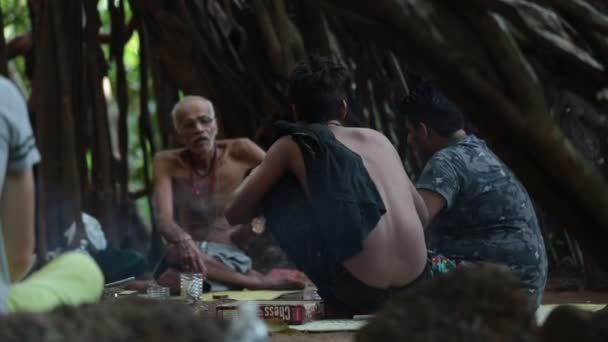 Arambol, Goa, India - Novomber 30, 2017: indiai baba és az ő barátja, ült a tűz és a dohányzás füvet nagy banyan fa alatt — Stock videók