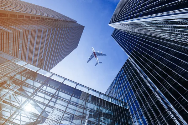 Avión volando sobre rascacielos de negocios . Fotos de stock libres de derechos