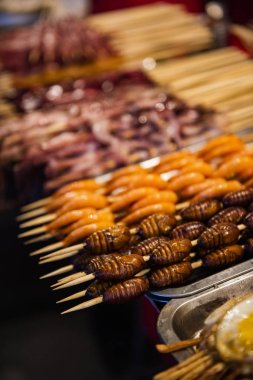 Pekin, Çin 'de bir gıda pazarında ızgara ve kızarmış ipek böceği pupası..