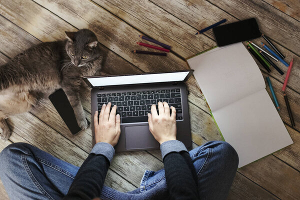 Woman with a cat sitting on floor and using laptop
