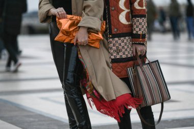 Paris, France - February 29, 2020: Neon orange clutch bag and striped Burberry handbag - streetstylefw20 clipart