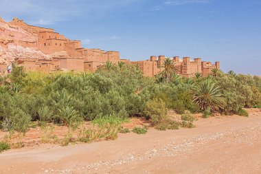 Ait Benhaddou Çarı 'nda kurumuş bir nehir yatağı, güçlendirilmiş binalar ve vaha manzarası.