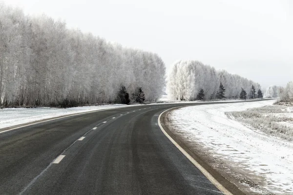 太い霜で覆われた木々の間の高速道路 — ストック写真