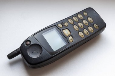 Eski hücresel tuşlu telefon beyaz pencere pervazına yakın plan.