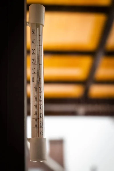 An outdoor window thermometer hangs under the roof of the veranda.