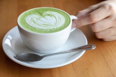 Ahşap arka plan üzerine bir fincan yeşil çay Matcha latte.