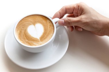 Latte sanat kalp şekli üzerinde beyaz backgr fincan kahve tutan el