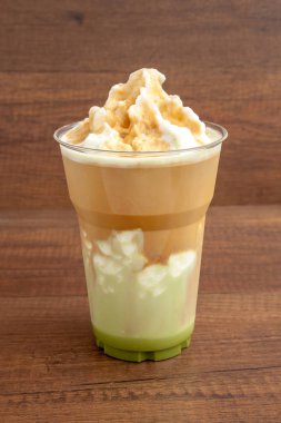 Ahşap backgr üzerinde plastik bardakta Matcha ve espresso frappe