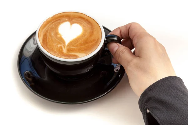 Kaffeetasse mit herzförmigem Latte Art auf der Oberseite, die Hand hält das c — Stockfoto