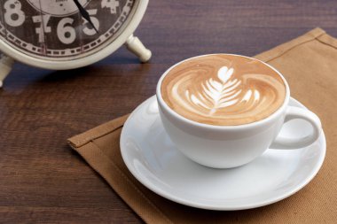 Rosetta latte sanat kahve fincanı yer peçeteye ahşap masa üstünde.