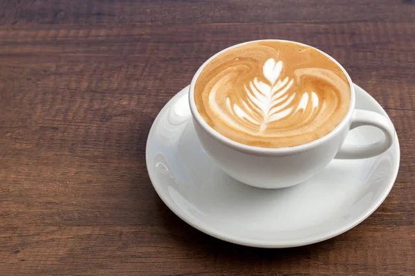 Xícara de café de arte latte roseta em fundo de madeira com espaço de cópia . — Fotografia de Stock