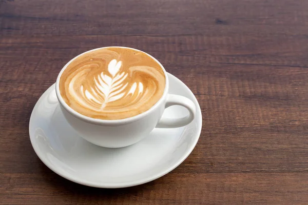 Taza de café de arte latte roseta sobre fondo de madera con espacio de copia . — Foto de Stock