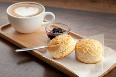 Latte sanat çörekler ve ev yapımı blueberr eşliğinde kahve fincanı