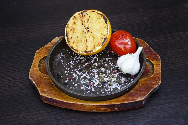 Izgara limon, domates ve sarımsak bir dökme demir fryin içinde otlar ile
