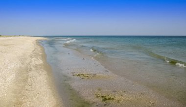 Sıcak bulutsuz bir günde dalgalar kıyıya haddelenmiş kumlu plaj