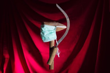 Tıbbi maskeli bir orak ve çekiç. Dünya proletaryasının sembolü, salgın, salgın zamanlardaki komünist arması..