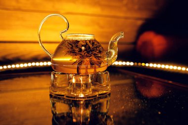 Kafede sıcak çay ve nilüfer çiçeği olan cam çaydanlık.