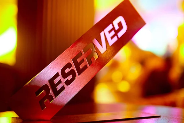 a metal reservation plate stands from the edge on a wooden table in a cafe-restaurant and club