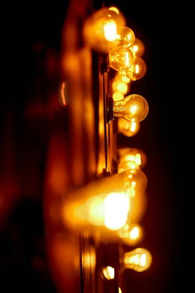 Accogliente, illuminazione lampada in un'istituzione su una parete di legno. Lampadine di vetro brillano con una luce piacevole e calda — Foto Stock