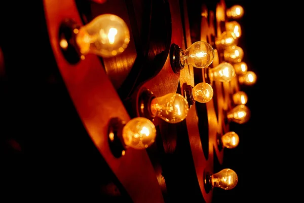 Gemütliche Lampenbeleuchtung in einer Institution an einer Holzwand. An der Decke hängende Glühbirnen erstrahlen in warmem Licht.. Stockbild