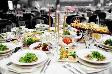 Şenlik masasında beyaz masa örtüleriyle kristal şarap bardakları ve yeşil sebze salatası var.