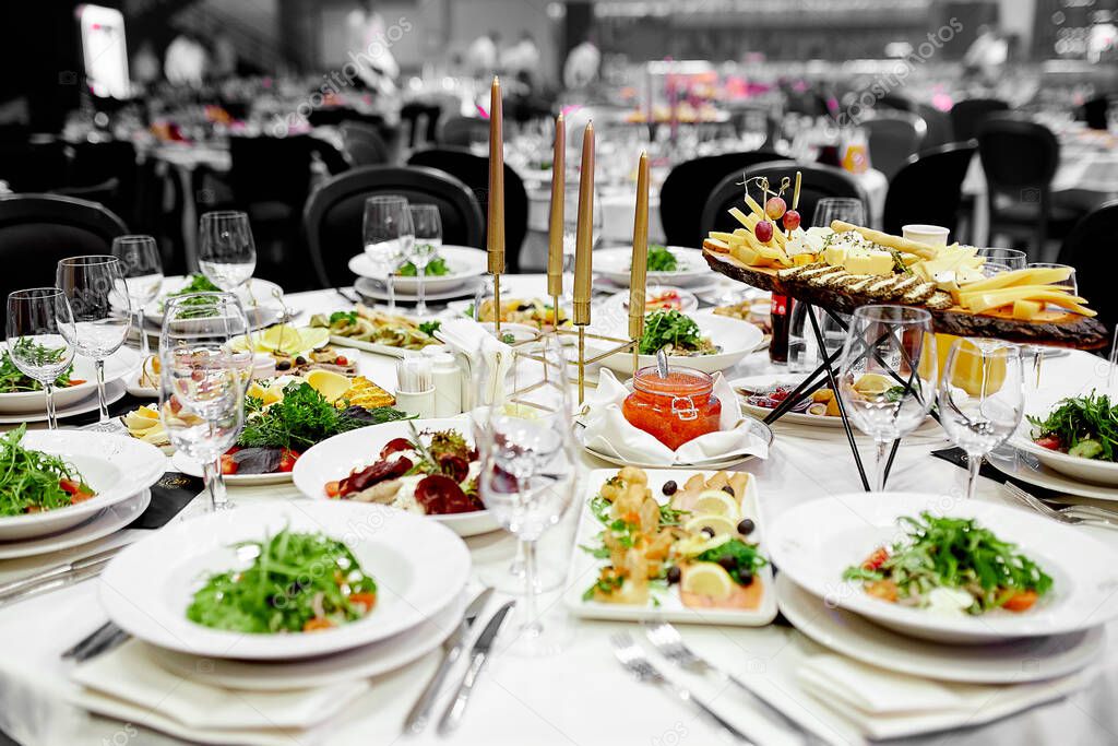 on the festive table with white tablecloths are crystal wine glasses and a green vegetable salad